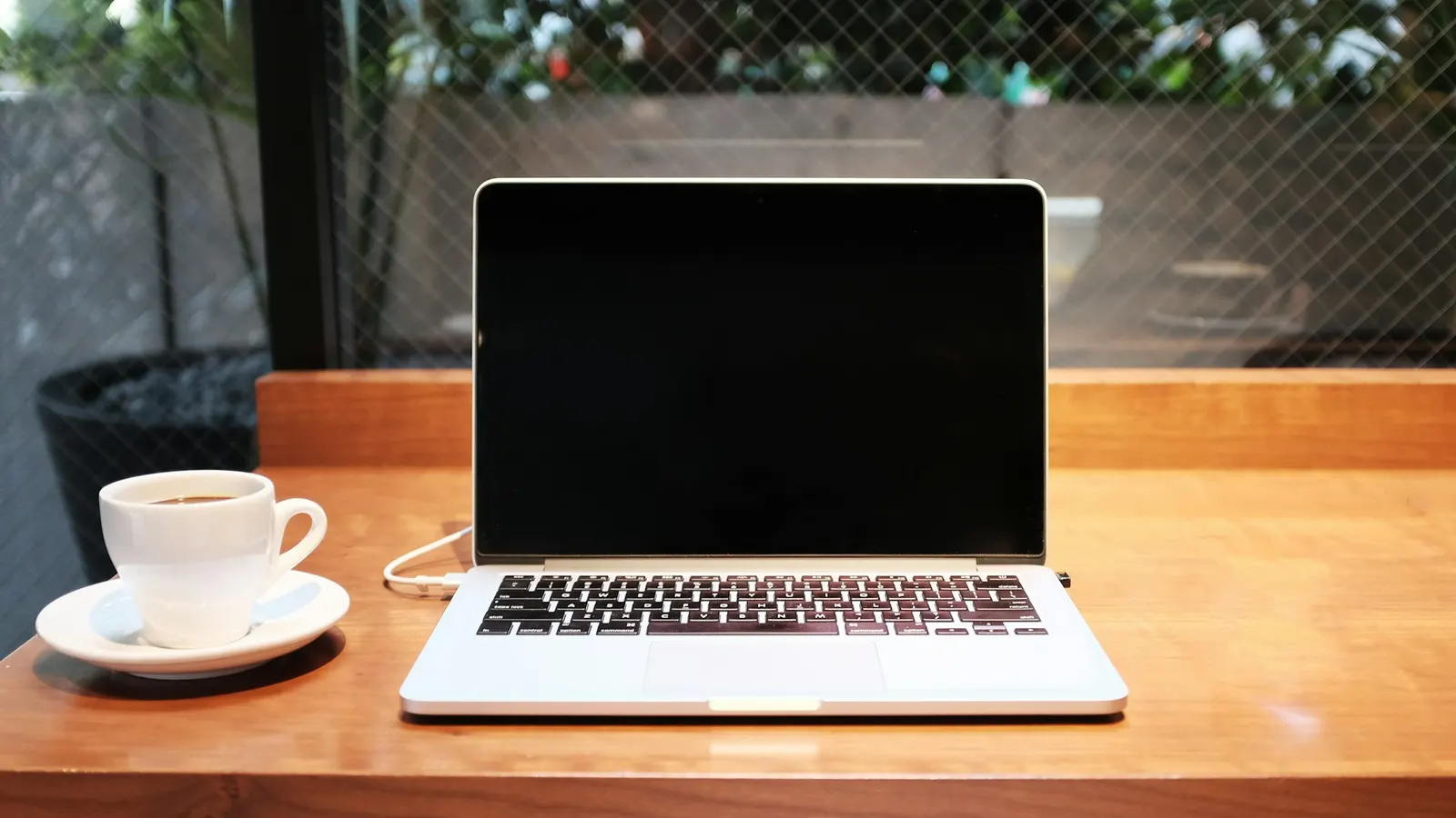 A laptop open on a desk beside a white coffee mug